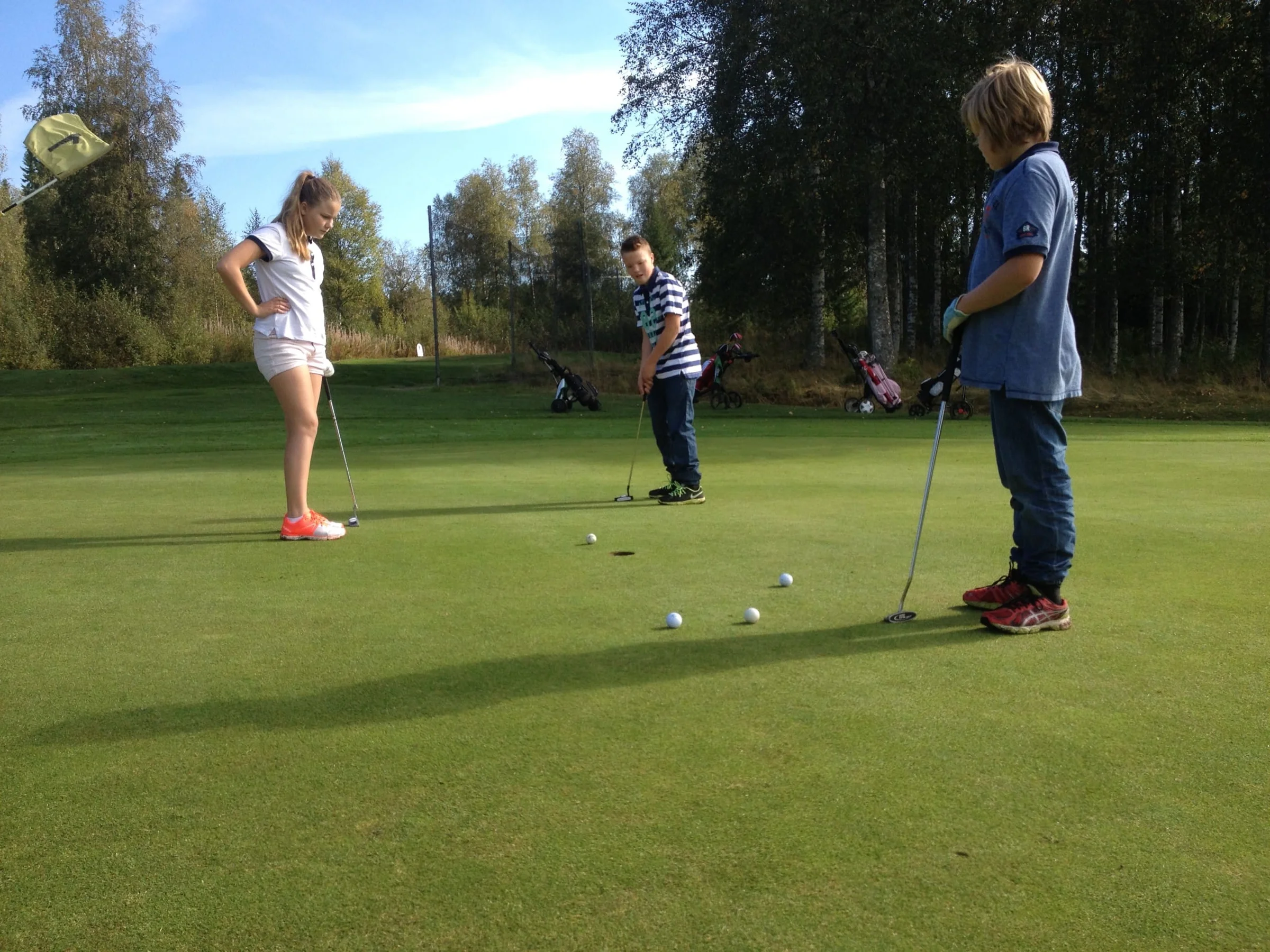 Evelina Östberg och William Näslund kollar när Elias Näslund puttar.